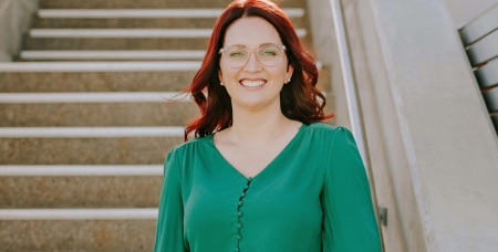 Image of Female employee of Byrne Lawyers standing on some steps in a green blouse smiling at the camera
