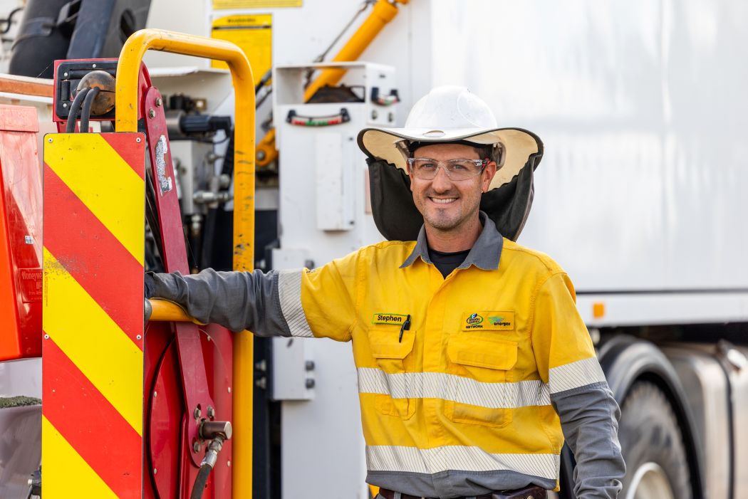 A man in safety google and helmet wearing an Ergon Energex hi vis unifomr. He stands beside machinery on the back of a utility truck