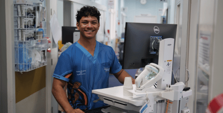 Young man in hospital setting standing next to medical equipment