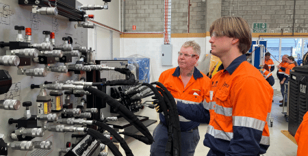 Two men in workshop environment in front of electrical equipment