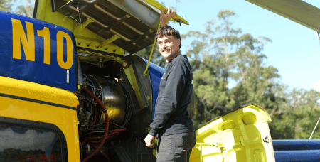 Young man in front of open aircraft engine